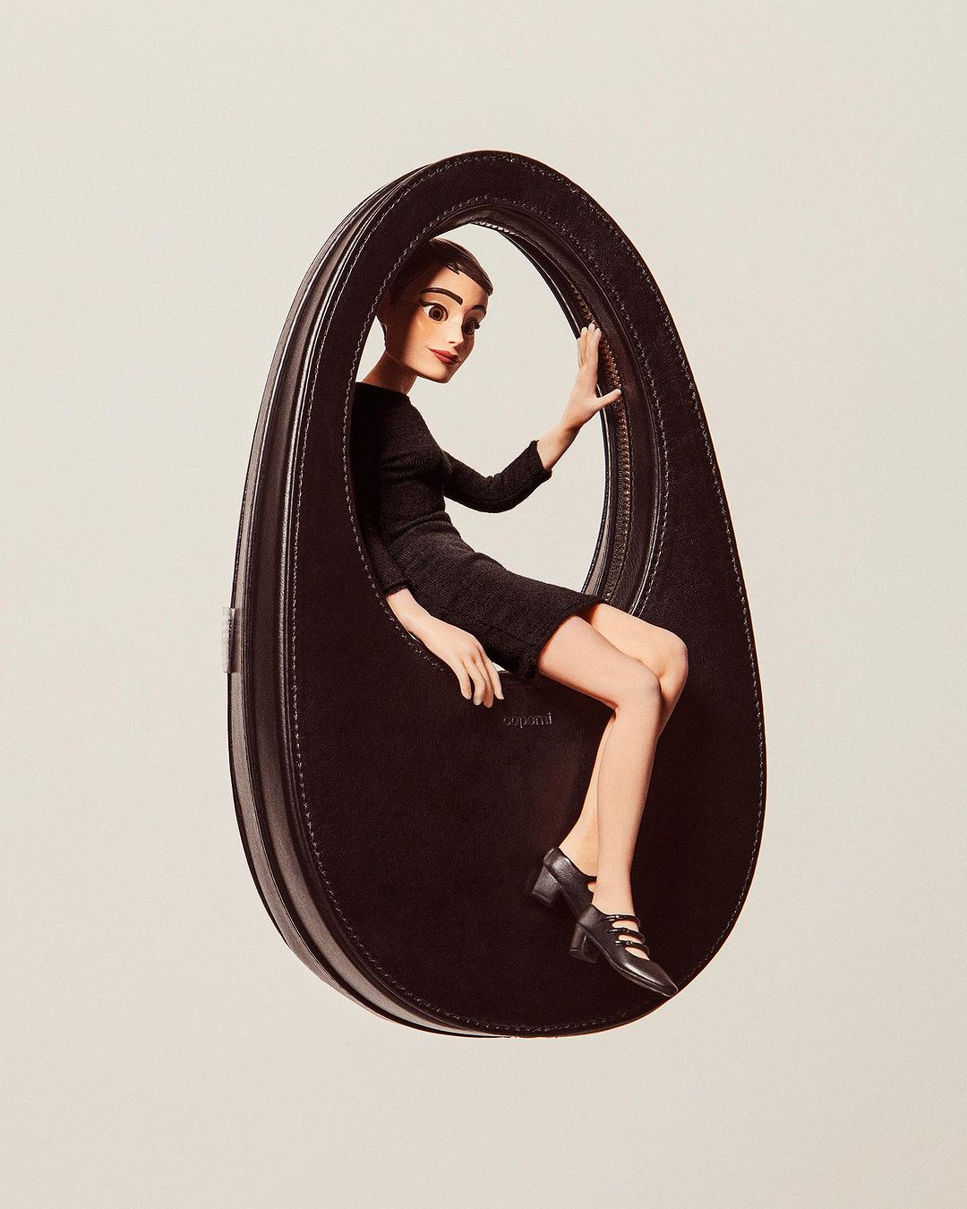 A fashion editorial image featuring a cartoon-style woman posing inside an oversized black leather handbag against a plain background.