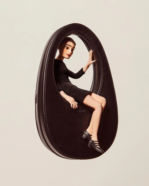 A fashion editorial image featuring a cartoon-style woman posing inside an oversized black leather handbag against a plain background.