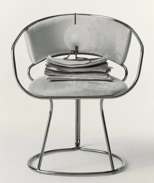 Chrome chair with gray cushion and a stack of newspapers topped with a small round lamp against a plain background in a studio setting.