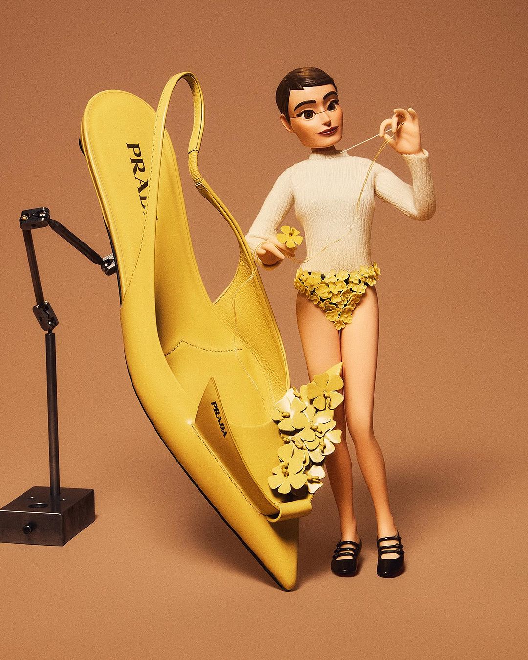 Fashion doll crafts a yellow stiletto heel shoe with floral embellishments on a taupe background, displayed on a metallic stand.