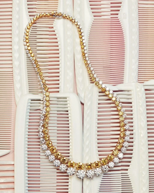 Elegant gold and diamond necklace on a backdrop of white combs, creating a striking contrast and texture.