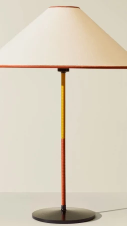 Minimalist table lamp featuring a conical cream shade with tan trim and a two-tone yellow and tan stand on a circular black base.