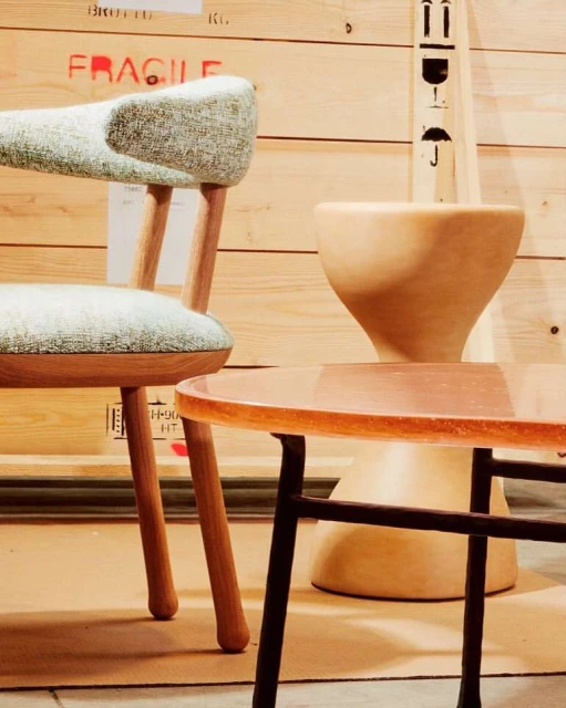 Wooden chair and round table displayed in front of a crate with red 'FRAGILE' text, creating a stylish interior design.