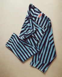 Folded blue and black striped jeans featuring a visible red label laid flat against a neutral textured background.