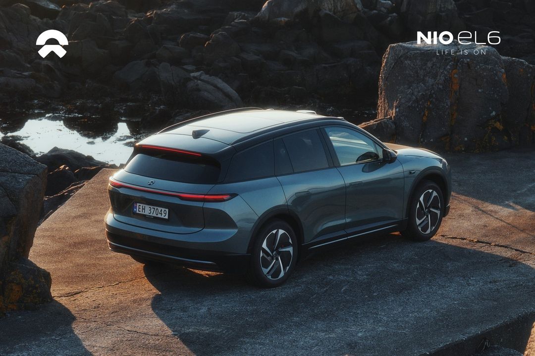 Electric blue NIO EL6 SUV on a rocky coastal landscape with diffused sunlight. Automotive photography featuring a contemporary car design.