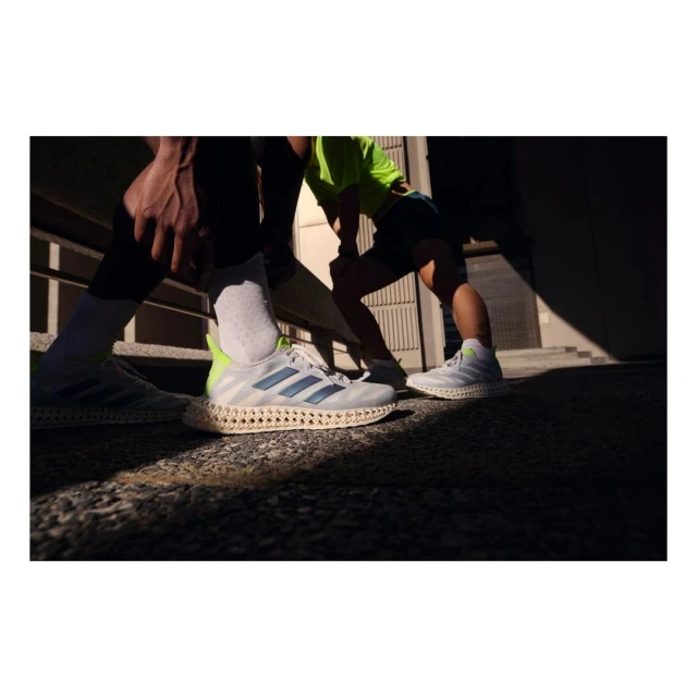 Three people wearing athletic shoes, captured in an outdoor urban setting with bright sunlight creating shadows on the ground.