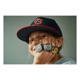 Close-up portrait of a child wearing a baseball cap and four championship rings across their fingers by photographer Florian Bison.