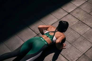 Woman in green and white athletic wear doing push-ups on grey tiled floor