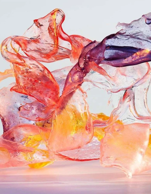 Abstract still life of translucent textured material in orange, yellow and purple hues against a white background, studio lighting.