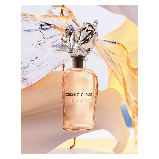 Louis Vuitton 'Cosmic Cloud' perfume bottle with silver ornamental cap, set against a light background with flowing fabric.