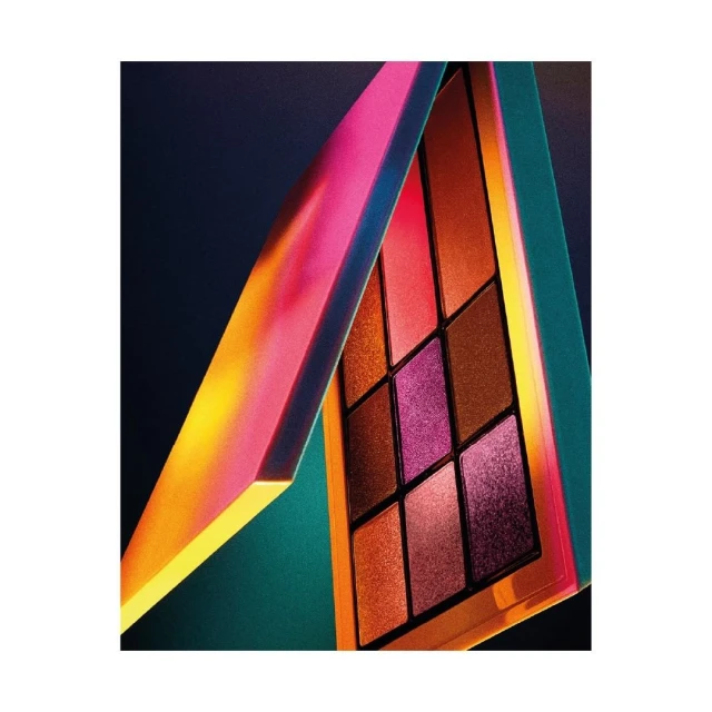 Eye shadow palette with various colors, including orange, purple, and brown, presented on a dark backdrop with iridescent lighting.