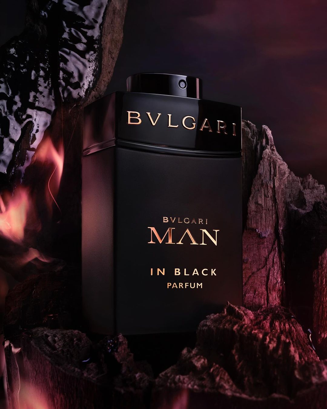 Elegant studio shot of Bvlgari Man In Black Parfum. Luxurious black bottle nestled among rugged rocks, creating a striking contrast.