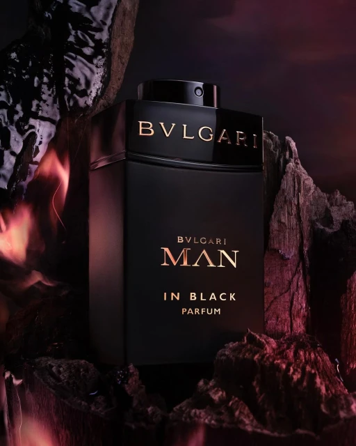 Elegant studio shot of Bvlgari Man In Black Parfum. Luxurious black bottle nestled among rugged rocks, creating a striking contrast.