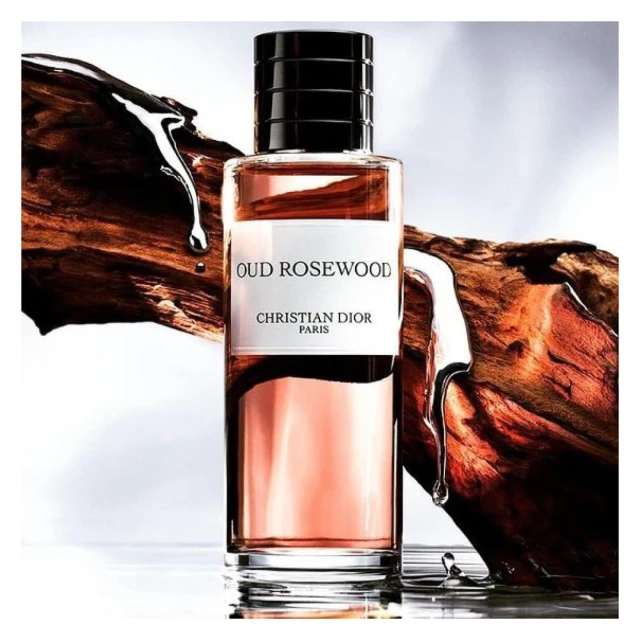 Product shot of Oud Rosewood fragrance by Christian Dior Paris, featuring a glass bottle, wooden accents, and clear liquid droplets.