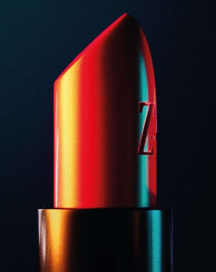 Close-up of a lipstick bullet in vibrant red, orange, and teal lighting against a dark background, photographed by Florian Joye.