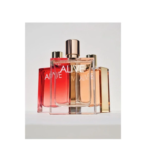 Several glass perfume bottles with gold accents and the word 'ALIVE' displayed on the front are arranged against a white background.