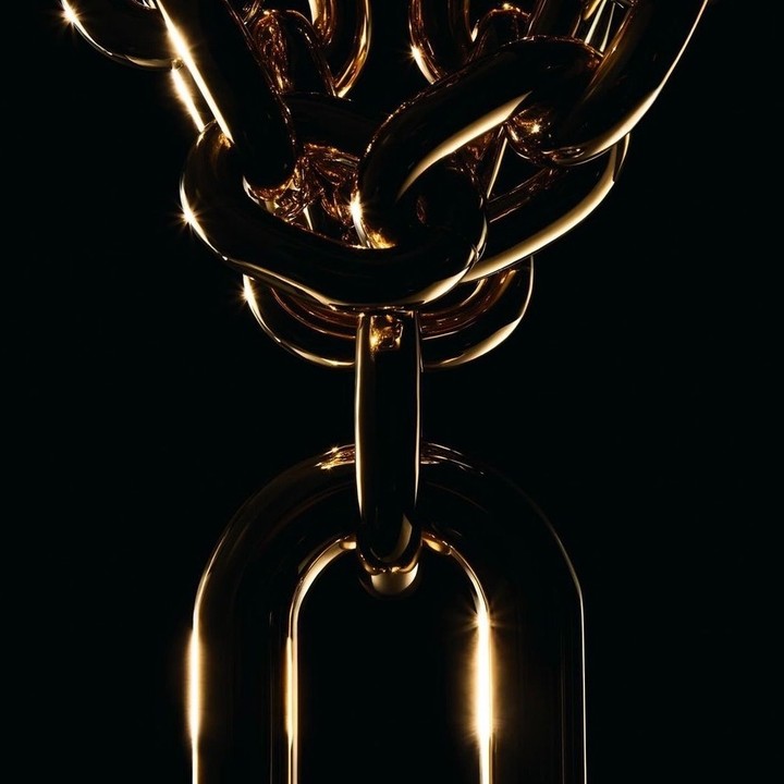 Dramatic, close-up product shot of a gold metal chain, featuring thick links and a glossy finish against a stark black background.