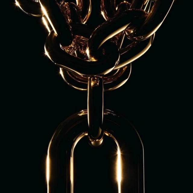 Dramatic, close-up product shot of a gold metal chain, featuring thick links and a glossy finish against a stark black background.
