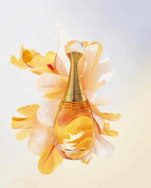Elegant perfume bottle with gold accents surrounded by soft yellow flower petals on a light background in a beauty advertisement.