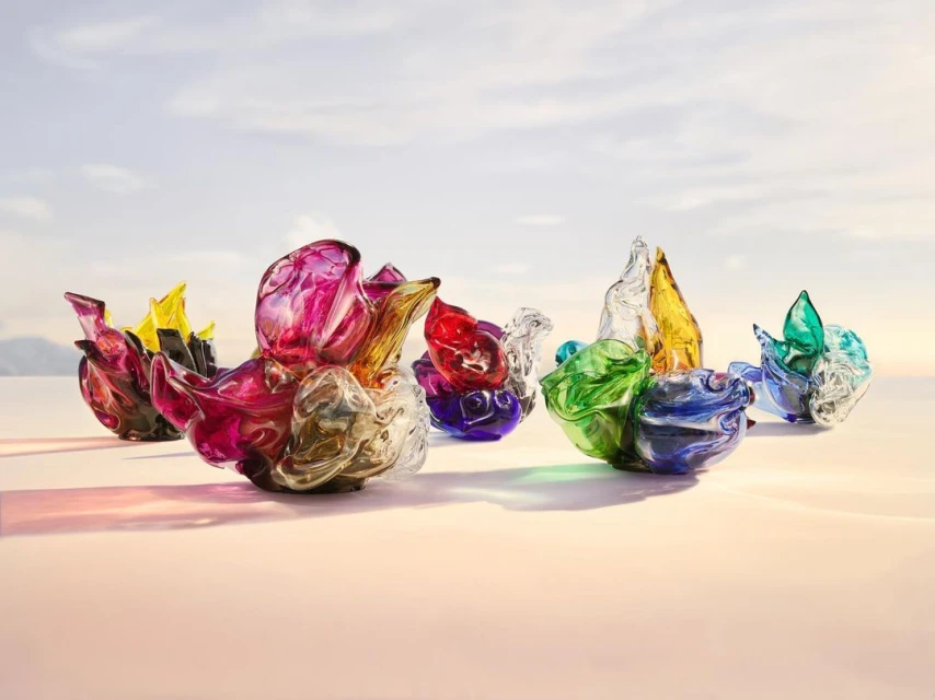 Colorful decorative glass art pieces arranged on a light surface against a bright, soft sky backdrop, creating a modern and artistic display.