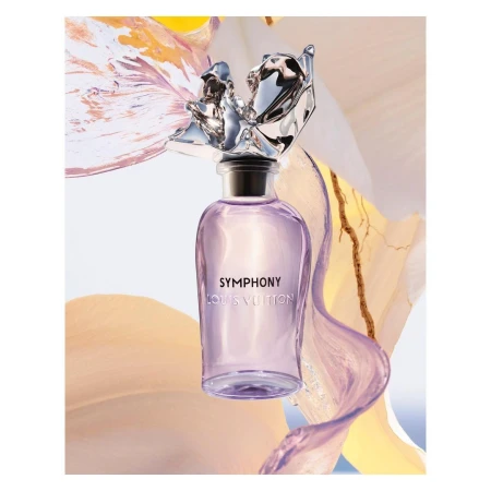 Louis Vuitton's Symphony perfume bottle in a studio shot with floral accents. The bottle is clear with a silver stopper. Fashion beauty shot.