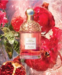 Perfume bottle surrounded by vibrant red pomegranates and rippling water shot by Florian Joye
