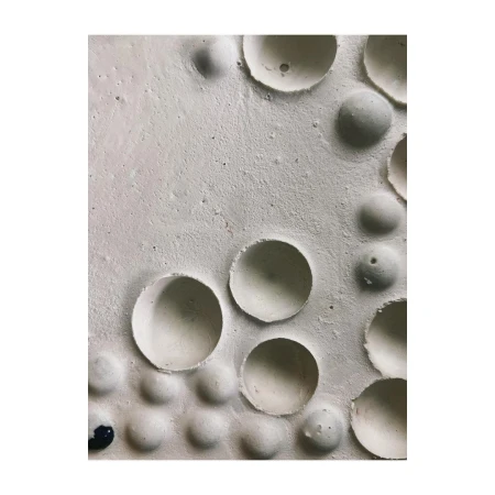 Abstract textured surface with spherical and hemispherical indentations in off-white tones, creating a tactile, minimalist composition.