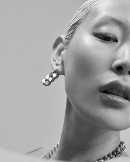 Monochrome studio shot of a model wearing chunky chain-link earrings and necklace, showcasing contemporary fashion jewellery.