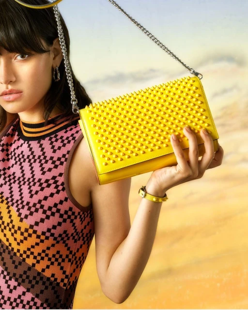 Studio shot of an Asian woman in patterned tank top holding a yellow studded purse with silver chain. Fashion and beauty.