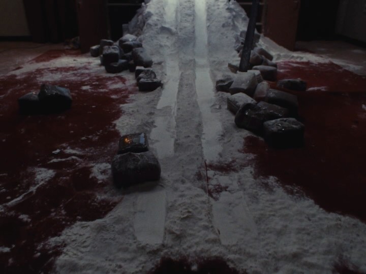 Interior setting with a mix of white powder or snow along with dark stones on a dark red surface, creating a stark contrast.