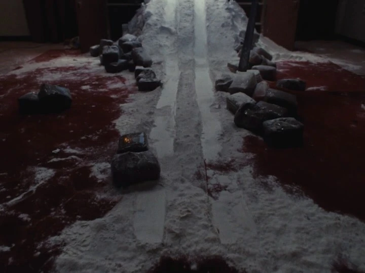 Interior setting with a mix of white powder or snow along with dark stones on a dark red surface, creating a stark contrast.