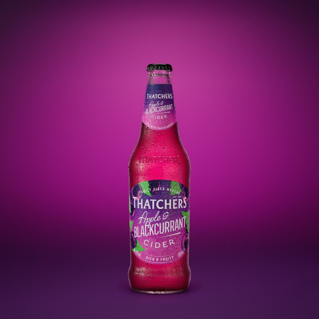 Bottle of Thatcher's Apple & Blackcurrant Cider with condensation on a purple background. The cider bottle is centered.