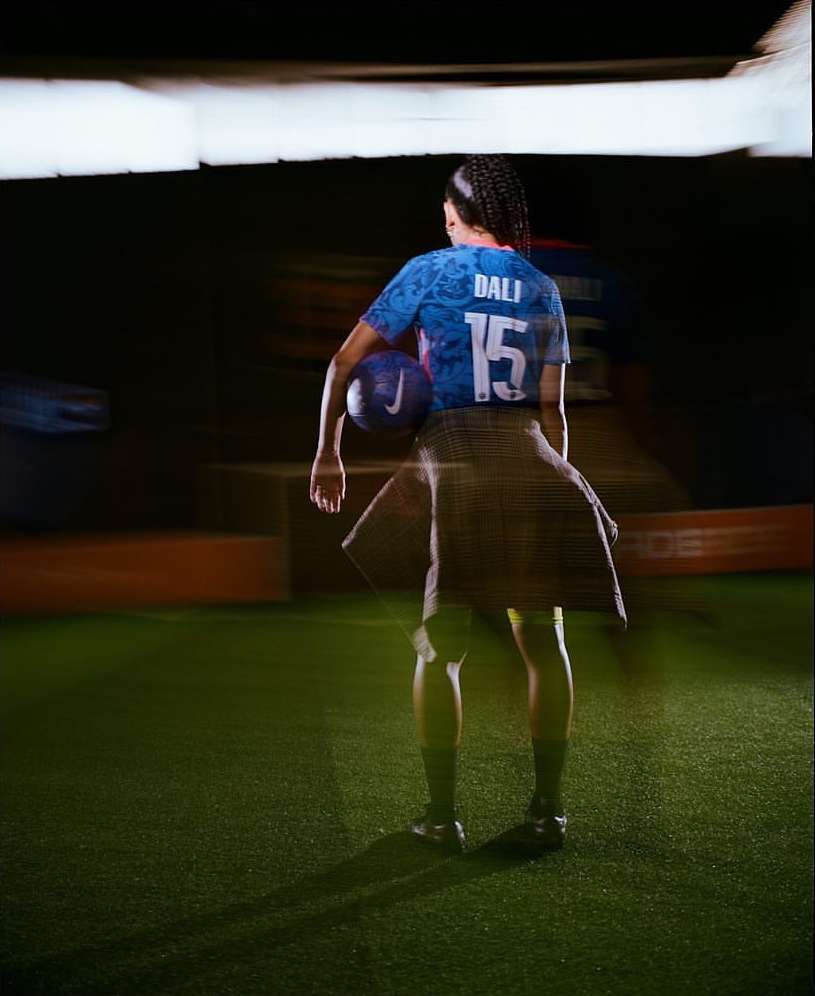 Female soccer player in a sports jersey with the number 15, holding a soccer ball, standing on a green turf field.