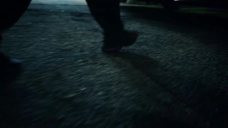 Low angle shot of dark running shoes walking on asphalt pavement at night in London
