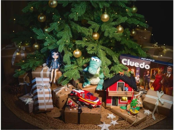 Festive Christmas tree scene with gift-wrapped presents, holiday ornaments, doll, and Cluedo game box underneath, creating a cheerful mood.