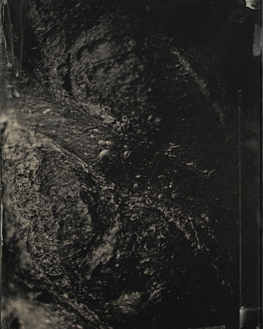 Abstract landscape featuring a dark, textured, and possibly mountainous terrain with visible stone-like formations and a stark, high-contrast rendering.