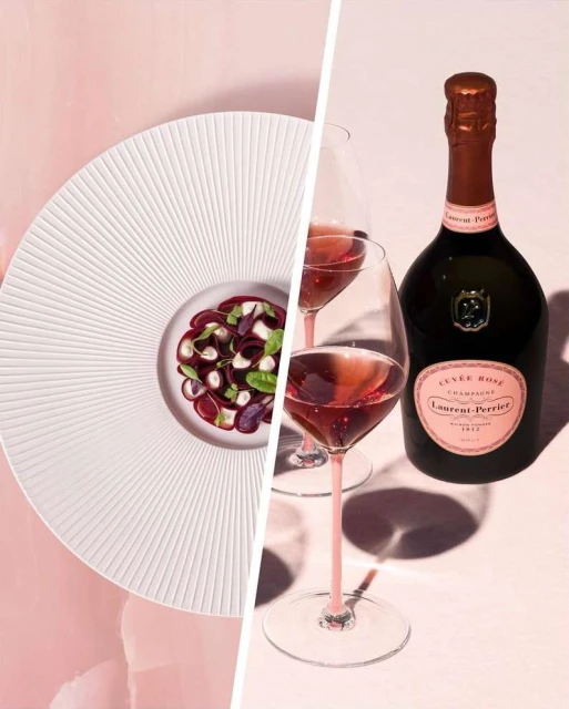 Elegant table setting featuring rose champagne in stemmed glasses alongside a plate of colorful salad on a split pink background.