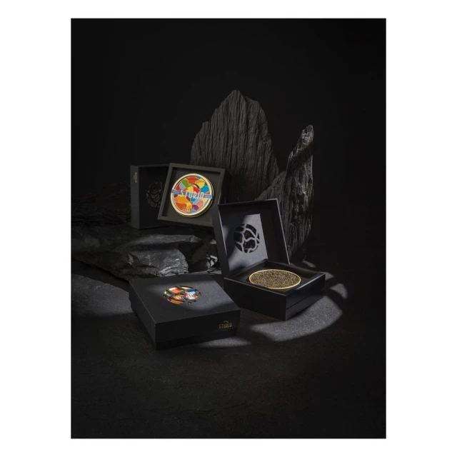 Four open black boxes display caviar, one featuring an abstract art lid, arranged against a dramatic black rock background.