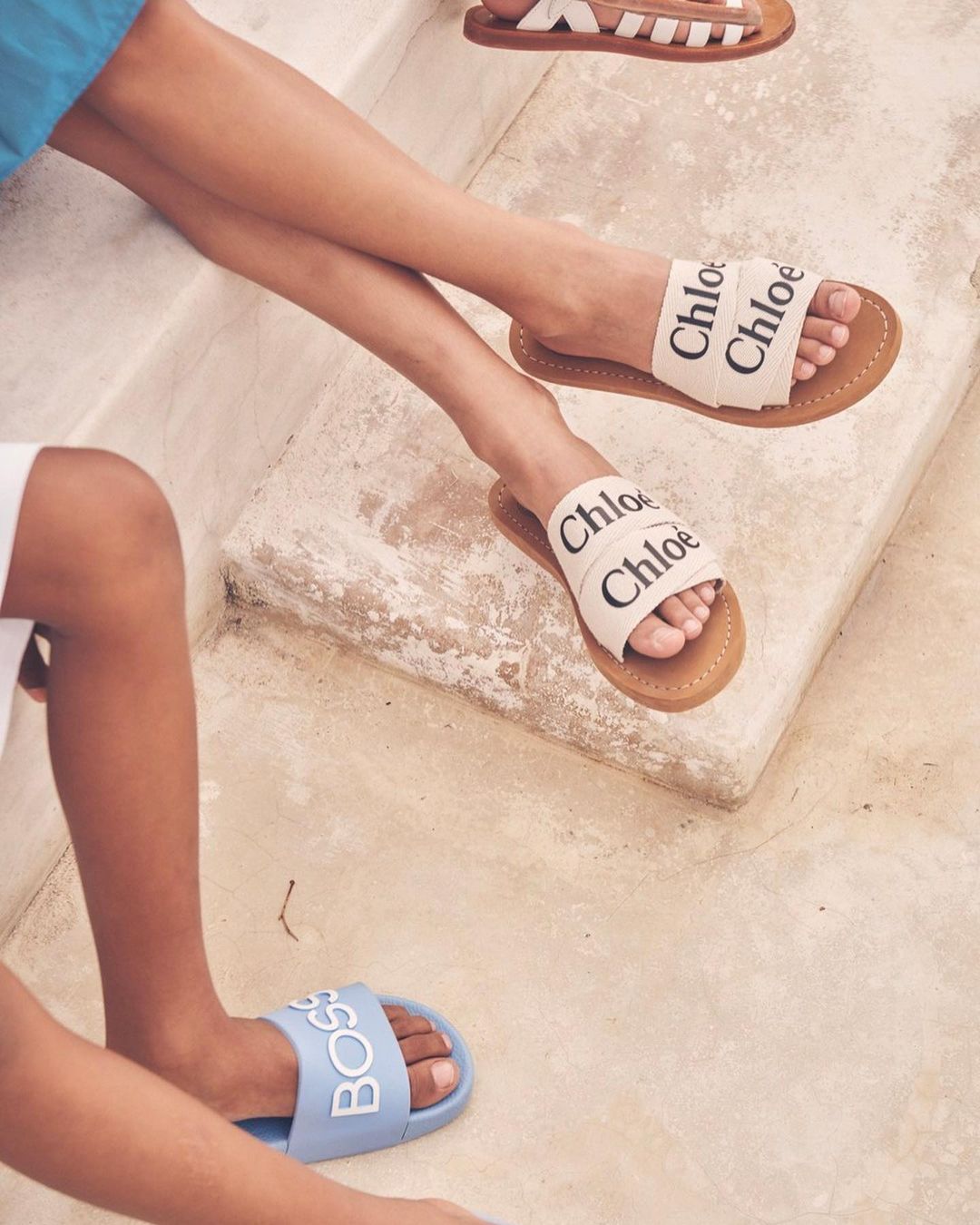Close-up of three pairs of women's fashion sandals in bright sunlight. Featured brands are Chloé and Boss.