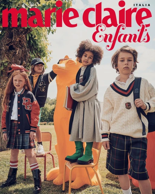 Marie Claire Enfants editorial shot with four children in school uniforms in an outdoor setting with a large orange animal sculpture.