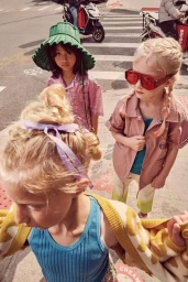 Three children in urban street setting wearing colourful clothing, photographed from high angle by Franck Malthiery in Milan.