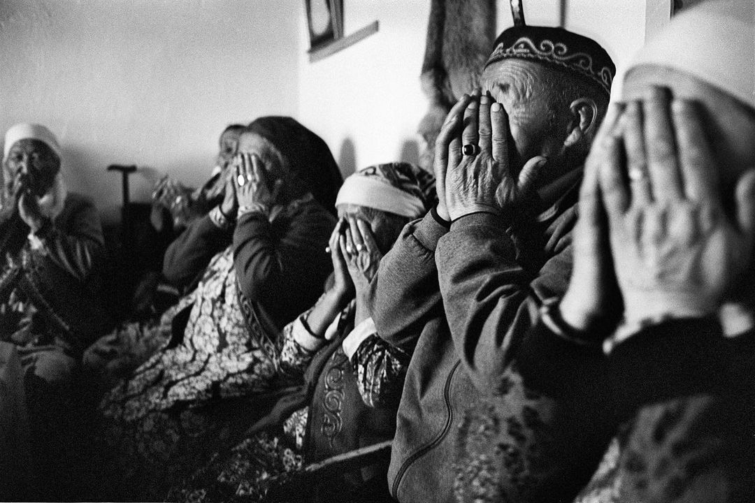 Black and white photo of several people with their hands covering their faces, creating a sense of mystery and anonymity.
