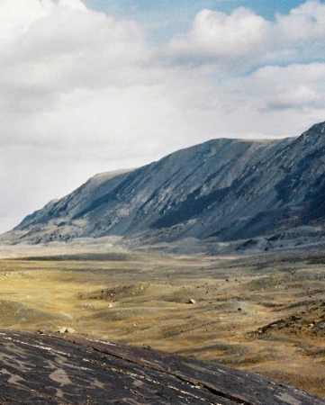 Vast mountain valley landscape with rugged slopes under an expansive cloudy sky photographed by Franck Pourcel in Paris