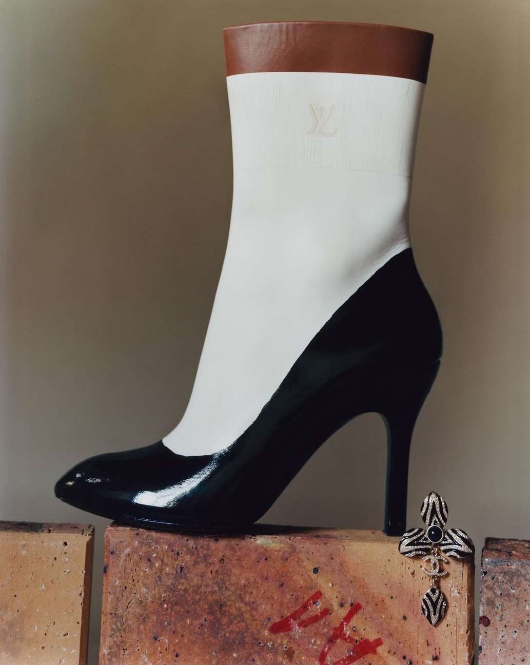 Fashionable shoe with black heel and upper part of white sock with brown top sitting on bricks, studio shot, still life.