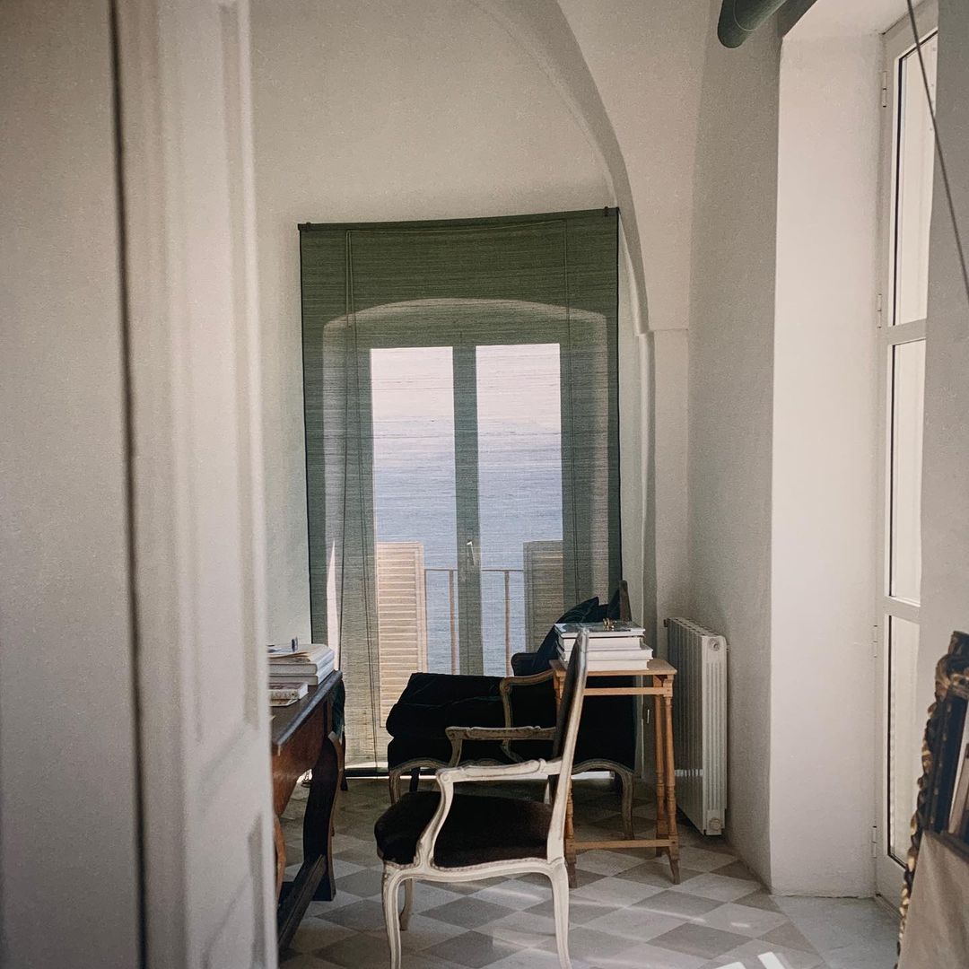 Sunlit room with sea view features a desk, chair, radiator, and tiled floor, creating a serene, inviting workspace.