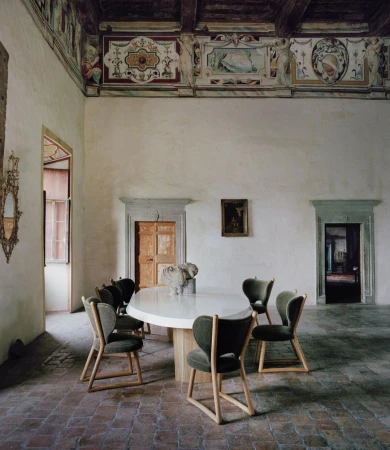 Interior photo of a dining room with white walls, arched doorways, tiled floors, and a wooden dining table with chairs. 