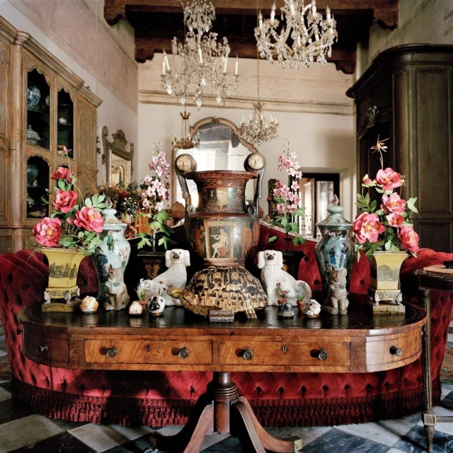 Elaborate interior scene featuring a wooden table adorned with vases, ceramic dogs, and a decorative turtle shell beneath chandeliers.