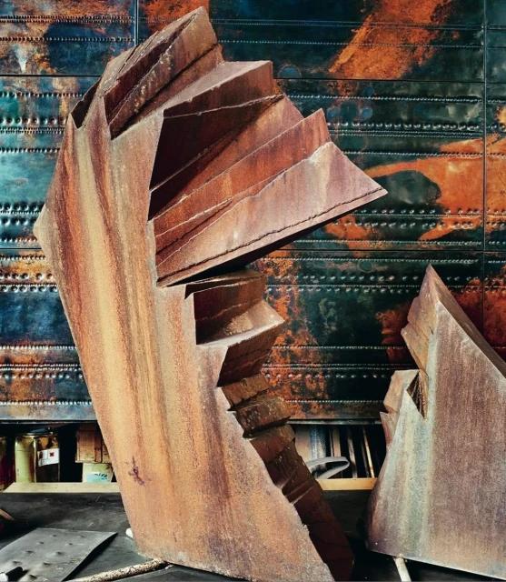 Abstract rusted metal sculpture in an indoor setting with industrial metal paneling. Close-up, textural details, and warm color palette.