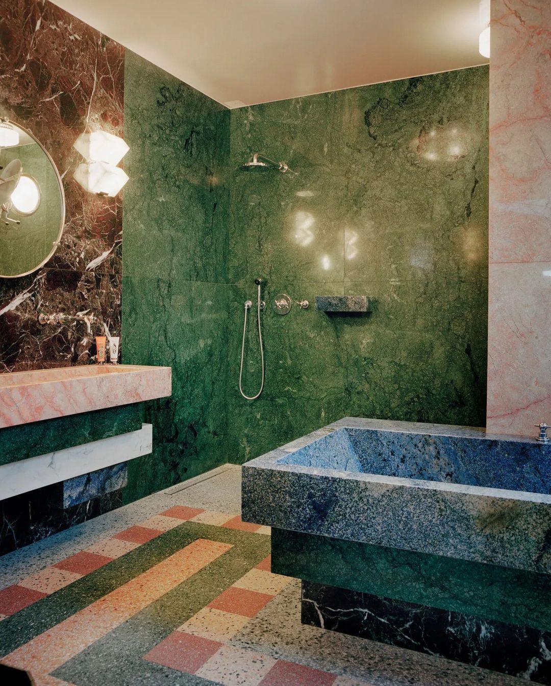 Luxurious bathroom featuring green and dark brown marble walls, custom sink, shower, and bathtub in a modern interior design.