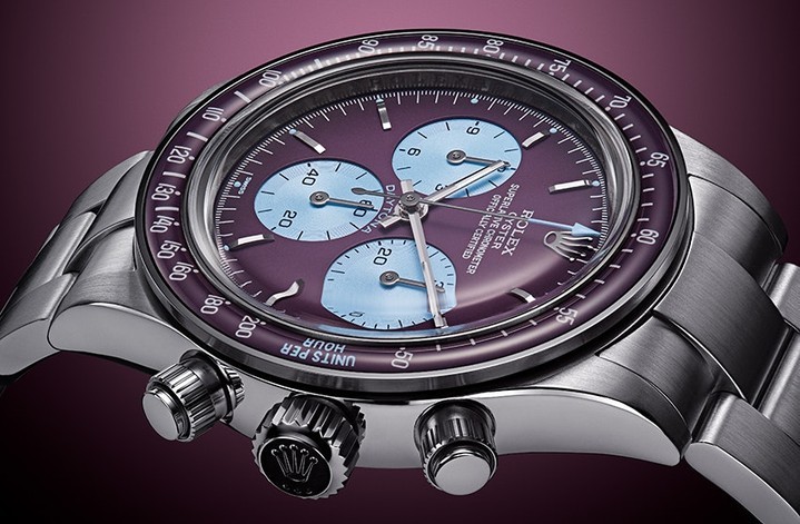 Close-up of a Rolex Daytona wristwatch with a stainless steel band, purple face, and light blue subdials on a dark background.